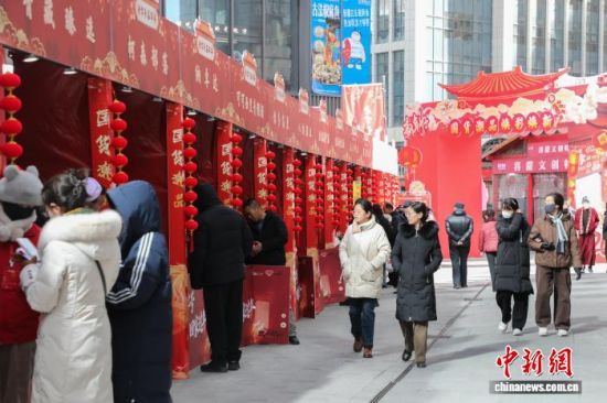 图为市民走过年货展台。马铭言 摄 图为市民走过年货展台。马铭言 摄